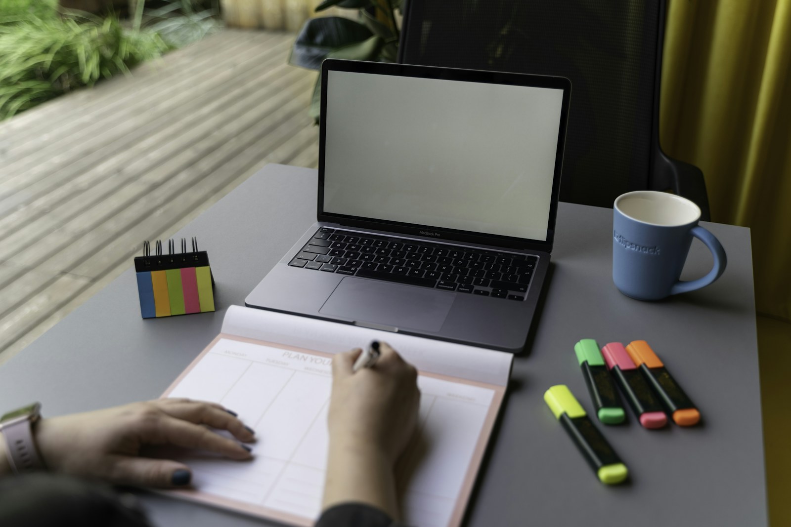 Person planning work beside a laptop and stationery