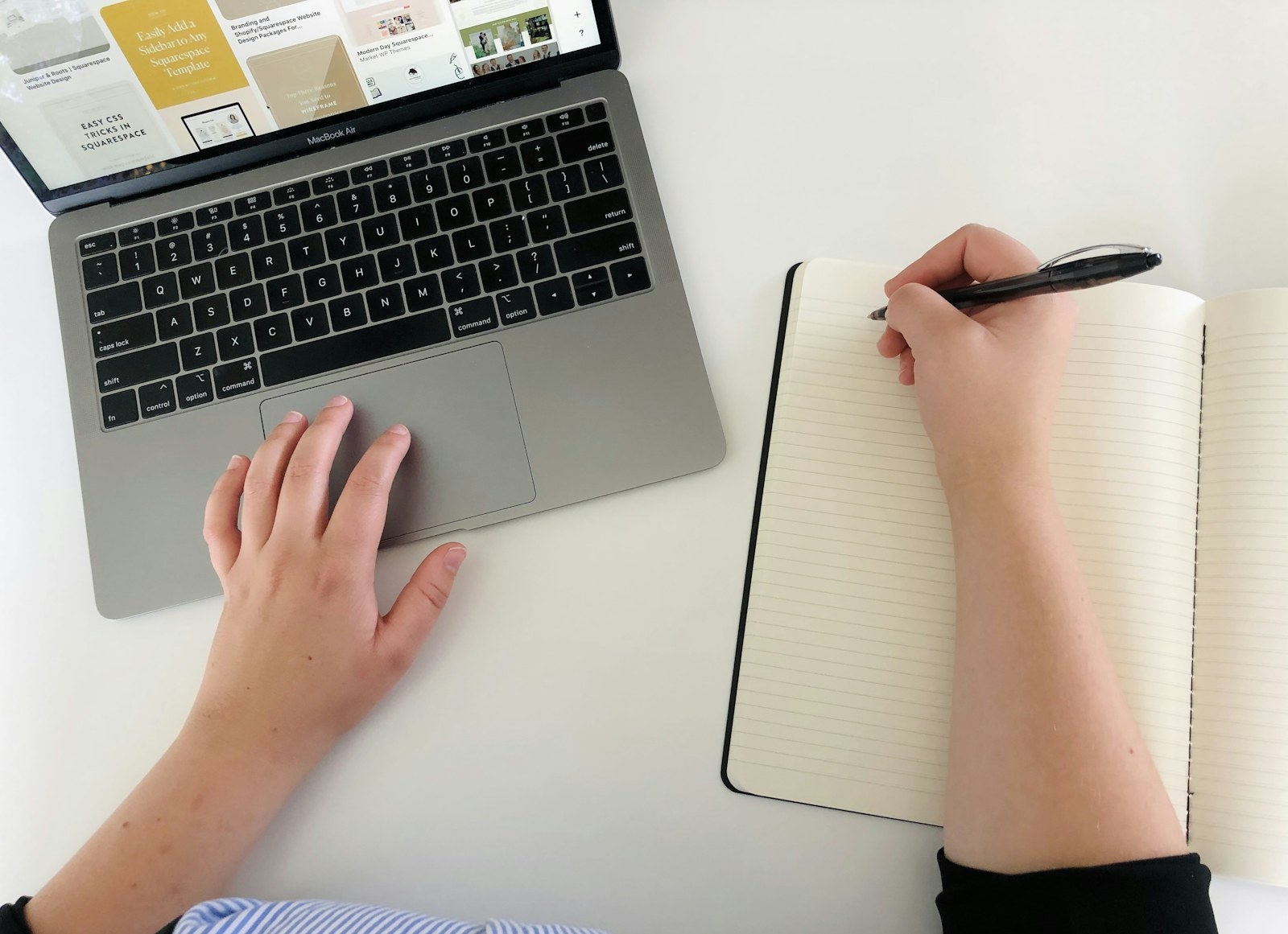 Writer researching on a laptop beside an open notebook